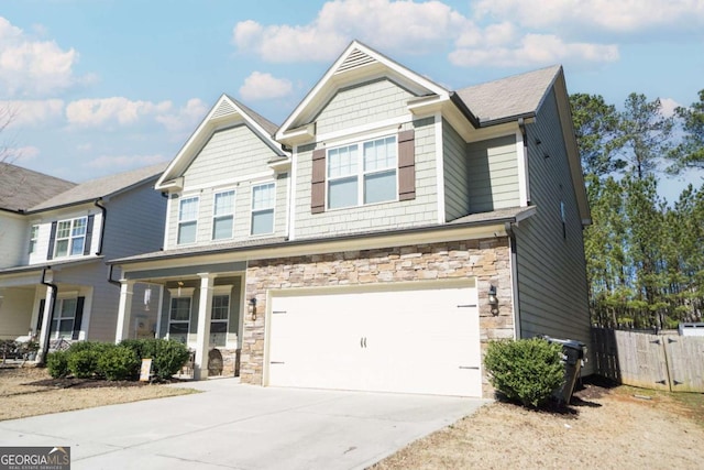 craftsman-style home with covered porch, fence, a garage, stone siding, and driveway