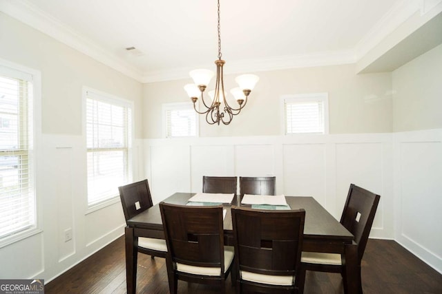 dining room with dark wood finished floors, visible vents, a decorative wall, ornamental molding, and a chandelier