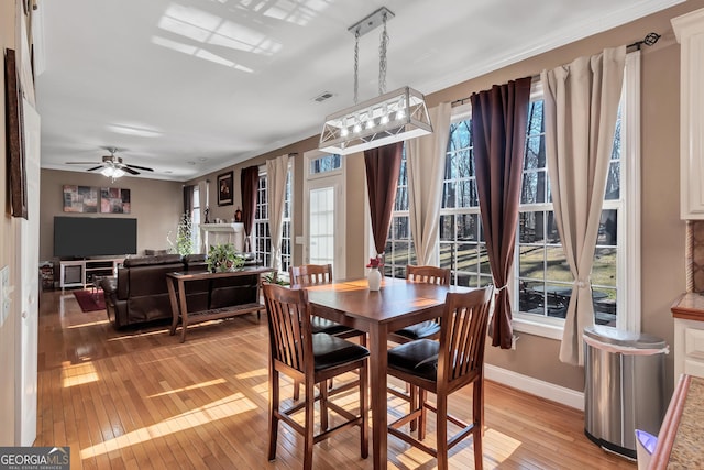 dining area featuring ceiling fan, visible vents, baseboards, light wood-style floors, and crown molding