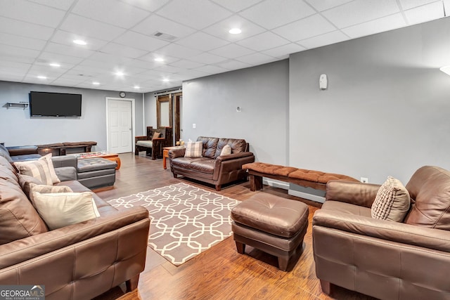 living room with a barn door, a paneled ceiling, recessed lighting, wood finished floors, and visible vents