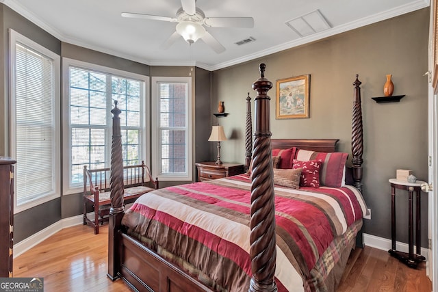 bedroom featuring baseboards, light wood-type flooring, visible vents, and crown molding