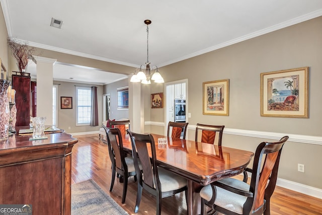 dining area with ornamental molding, light wood finished floors, decorative columns, and baseboards