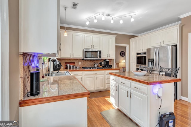 kitchen with visible vents, tile countertops, appliances with stainless steel finishes, crown molding, and a sink