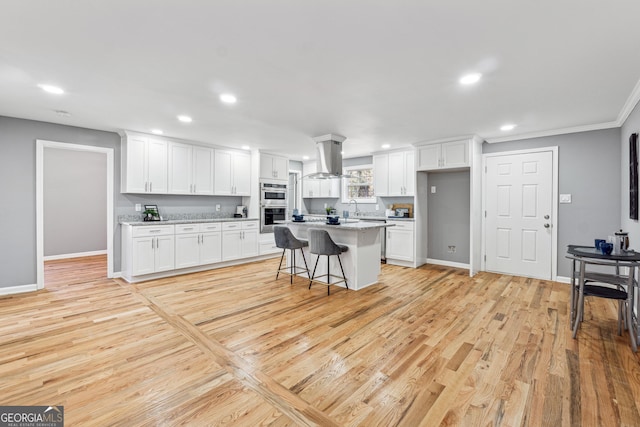 kitchen with light wood-style floors, recessed lighting, island exhaust hood, and white cabinets