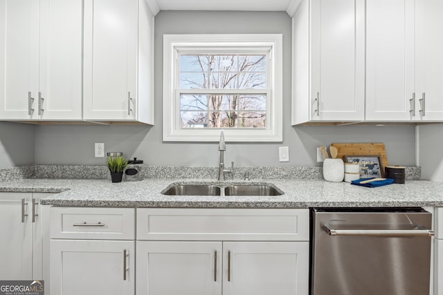 kitchen featuring white cabinetry, a sink, stainless steel dishwasher, and light stone countertops