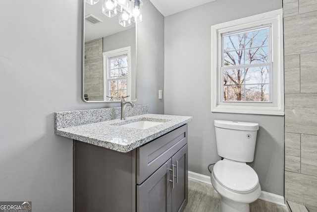 bathroom with visible vents, toilet, vanity, wood finished floors, and baseboards