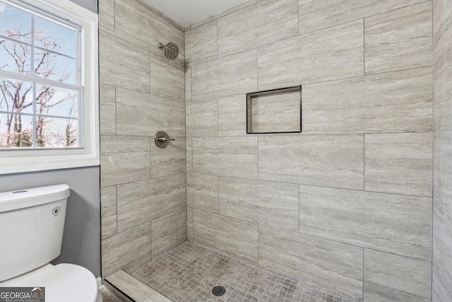 bathroom featuring a tile shower and toilet