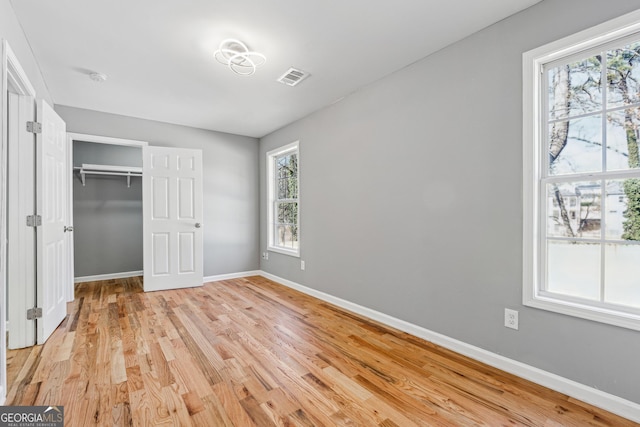 unfurnished bedroom featuring light wood-style flooring, a closet, visible vents, and baseboards