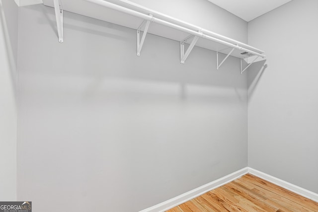 walk in closet with light wood finished floors