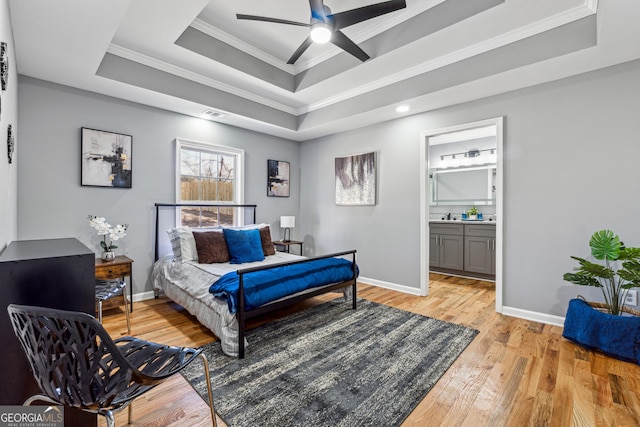 bedroom with visible vents, baseboards, ornamental molding, a tray ceiling, and light wood finished floors