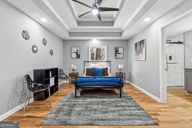 bedroom with ornamental molding, light wood-type flooring, a raised ceiling, and baseboards