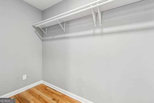 walk in closet with wood finished floors and attic access