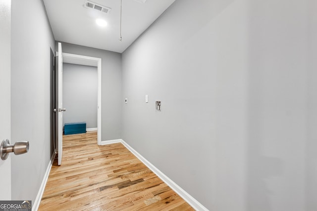 hall featuring attic access, light wood-type flooring, visible vents, and baseboards