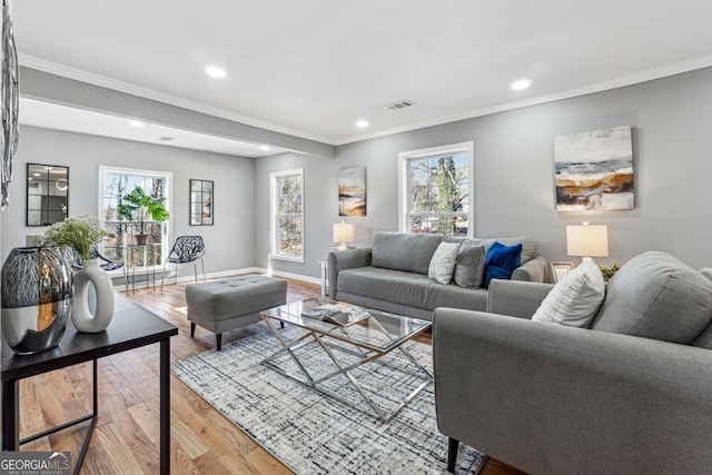 living room with visible vents, crown molding, baseboards, and wood finished floors