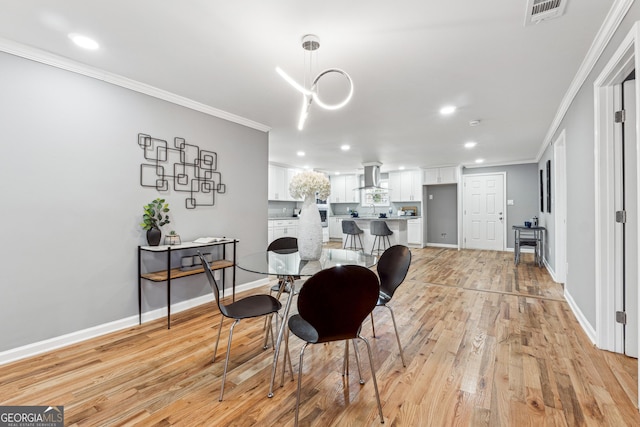 dining room featuring light wood finished floors, baseboards, visible vents, ornamental molding, and recessed lighting