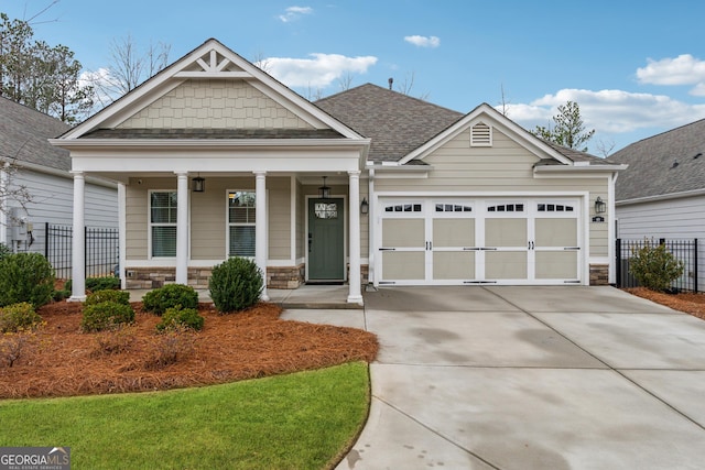 craftsman-style home featuring covered porch, concrete driveway, fence, and a garage