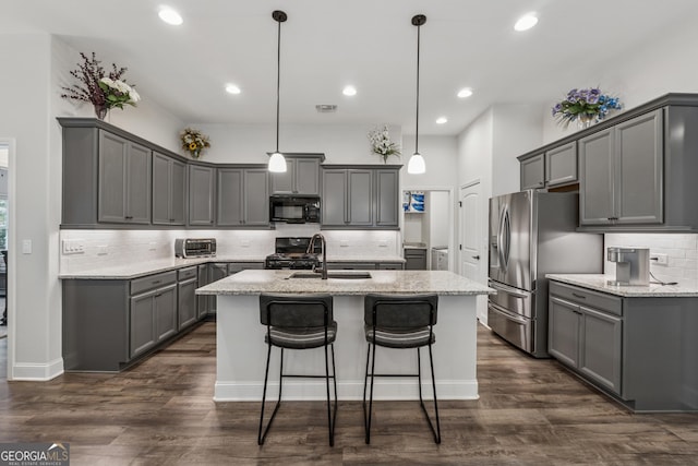 kitchen with a center island with sink, range with gas cooktop, gray cabinets, black microwave, and stainless steel refrigerator with ice dispenser