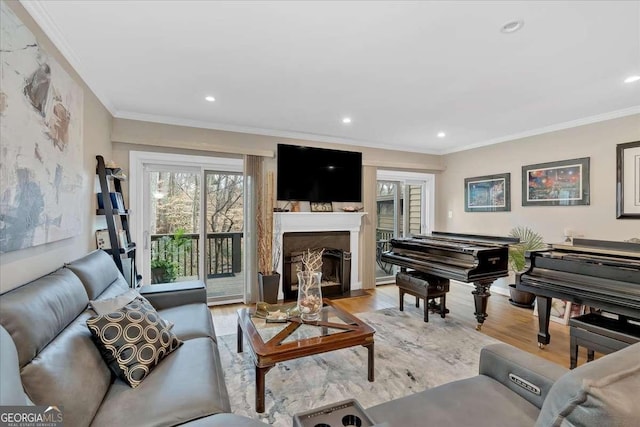 living area featuring light wood-style flooring, a fireplace, ornamental molding, and recessed lighting