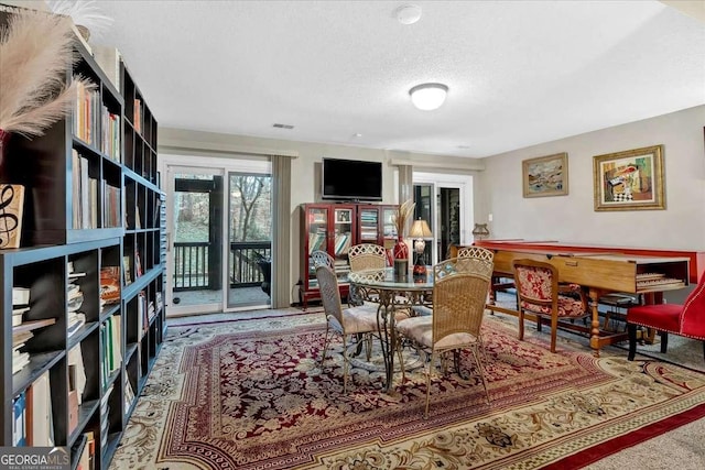 carpeted dining room with a textured ceiling and visible vents