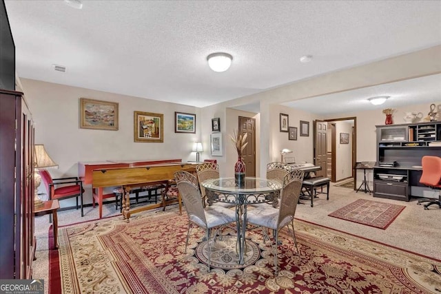 dining area with light carpet, a textured ceiling, visible vents, and baseboards