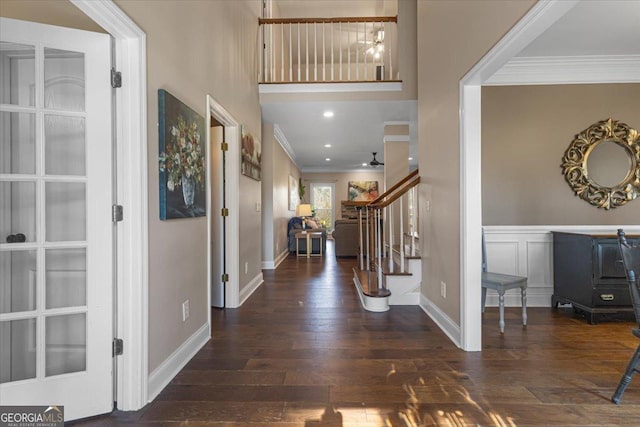 entrance foyer with crown molding, a decorative wall, a ceiling fan, hardwood / wood-style floors, and stairs