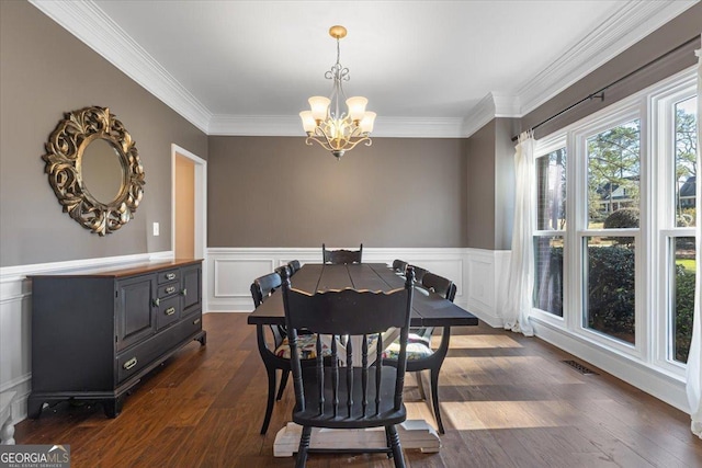 dining space featuring a notable chandelier, a wainscoted wall, visible vents, dark wood finished floors, and crown molding