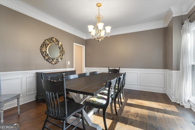 dining area featuring a wainscoted wall, ornamental molding, dark wood-style flooring, an inviting chandelier, and a decorative wall