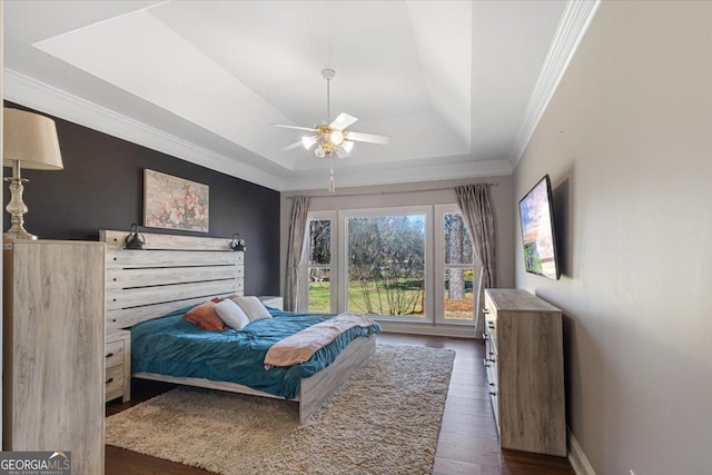 bedroom with ceiling fan, dark wood-type flooring, baseboards, a tray ceiling, and crown molding