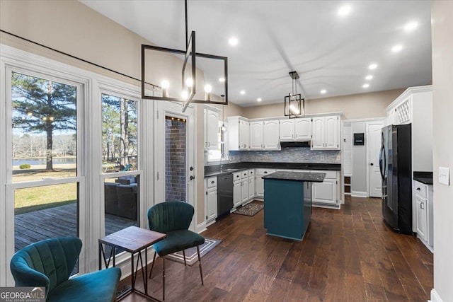 kitchen with dark countertops, decorative backsplash, a sink, a kitchen island, and black appliances