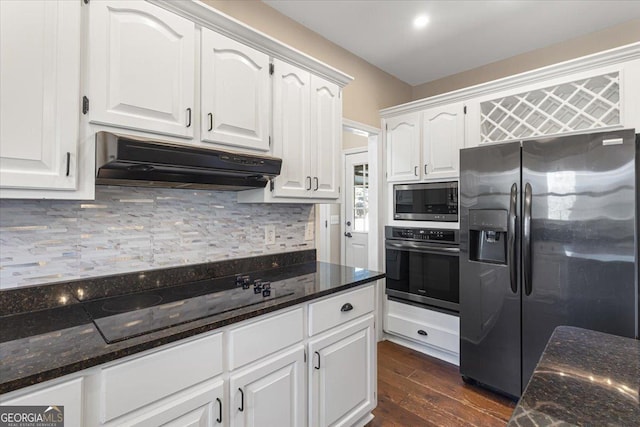 kitchen featuring white cabinets, dark stone counters, decorative backsplash, stainless steel appliances, and under cabinet range hood