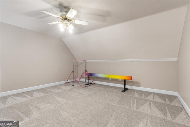 interior space featuring carpet, baseboards, vaulted ceiling, and a ceiling fan