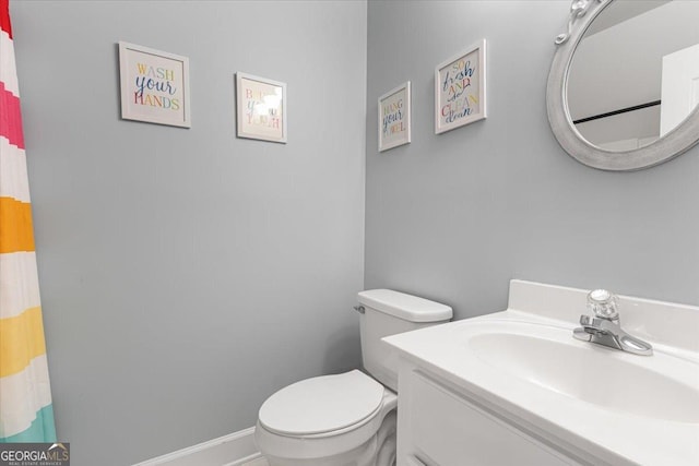 bathroom featuring baseboards, vanity, and toilet