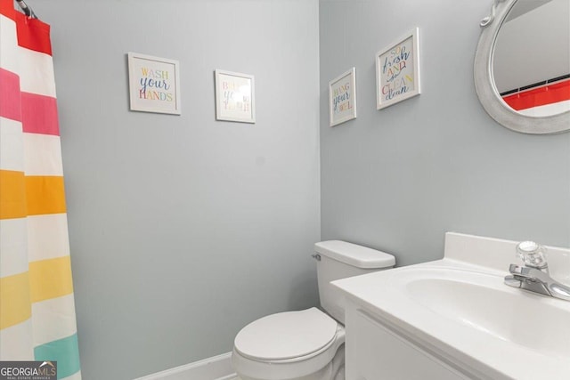 bathroom with baseboards, a shower with shower curtain, vanity, and toilet