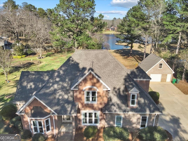 view of front of home with a shingled roof, a water view, and a detached garage