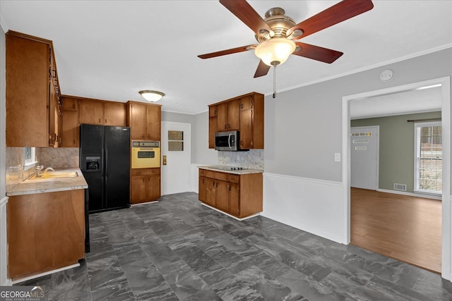 kitchen featuring visible vents, brown cabinetry, light countertops, black appliances, and a sink