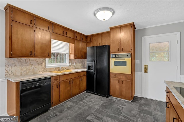 kitchen with black appliances, a sink, light countertops, and brown cabinets