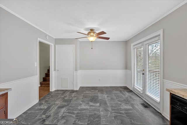 spare room featuring ceiling fan, marble finish floor, ornamental molding, and wainscoting