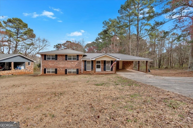 split level home with an attached carport, a front yard, concrete driveway, brick siding, and metal roof