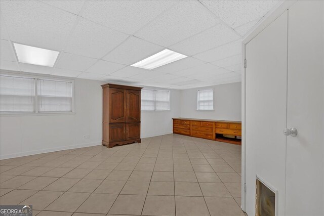 interior space with a drop ceiling and light tile patterned floors