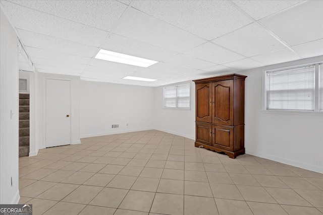 basement featuring stairway, a drop ceiling, and baseboards