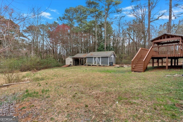 view of yard with an outbuilding, a wooden deck, a storage shed, and stairs