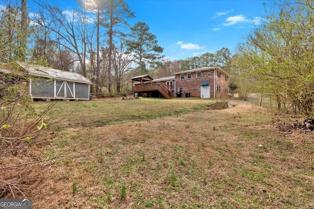 view of yard with an outbuilding, fence, a wooden deck, and stairs