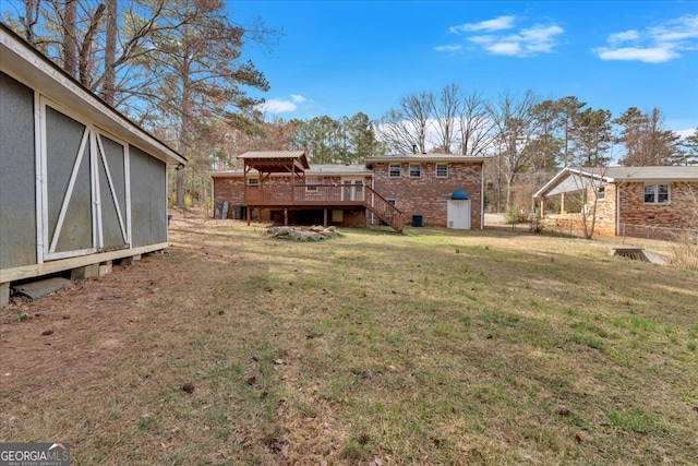 back of property featuring a yard, brick siding, and a wooden deck