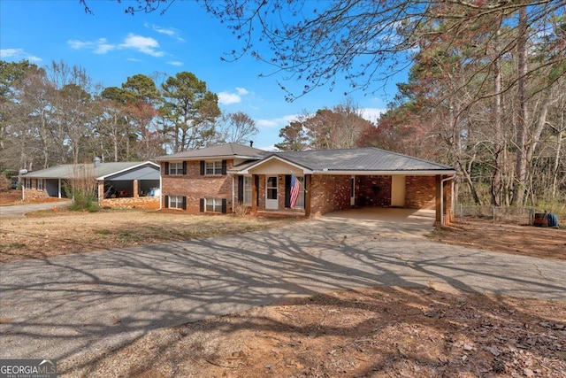 tri-level home with an attached carport, brick siding, and driveway