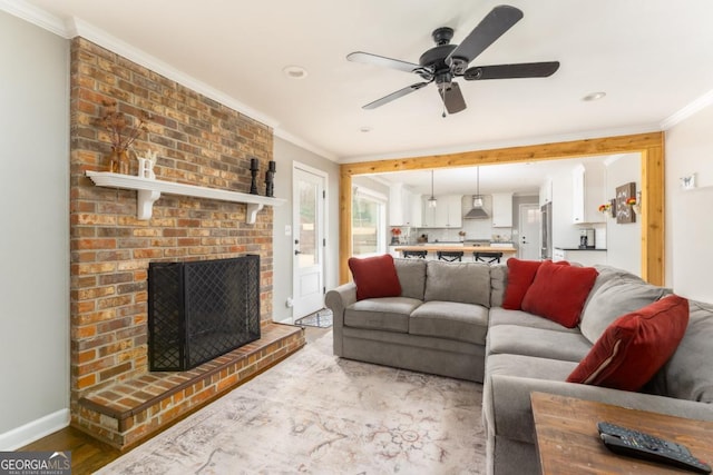 living area with a fireplace, crown molding, ceiling fan, wood finished floors, and baseboards