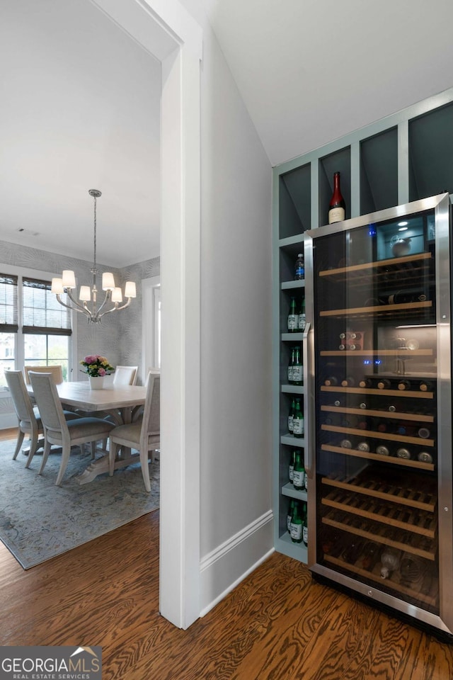 interior space featuring wine cooler, baseboards, an inviting chandelier, and wood finished floors