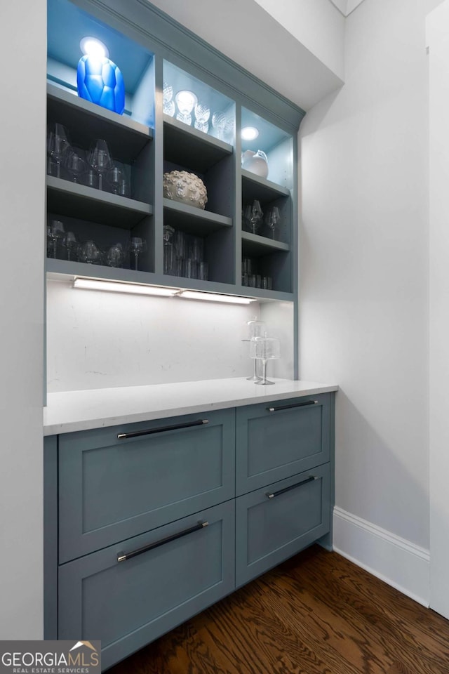 bar with dark wood-style flooring, baseboards, and a dry bar