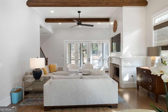 living room featuring a fireplace, beamed ceiling, baseboards, and wood finished floors