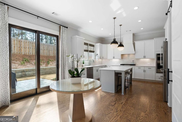 kitchen with a center island, stainless steel appliances, custom range hood, visible vents, and backsplash