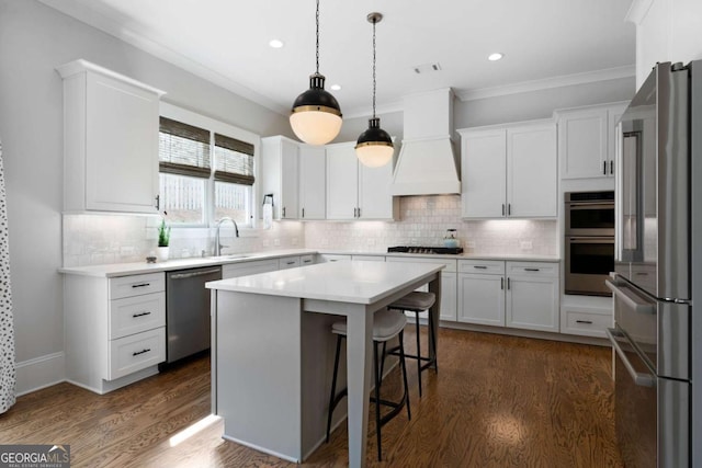 kitchen featuring premium range hood, appliances with stainless steel finishes, a sink, and white cabinetry